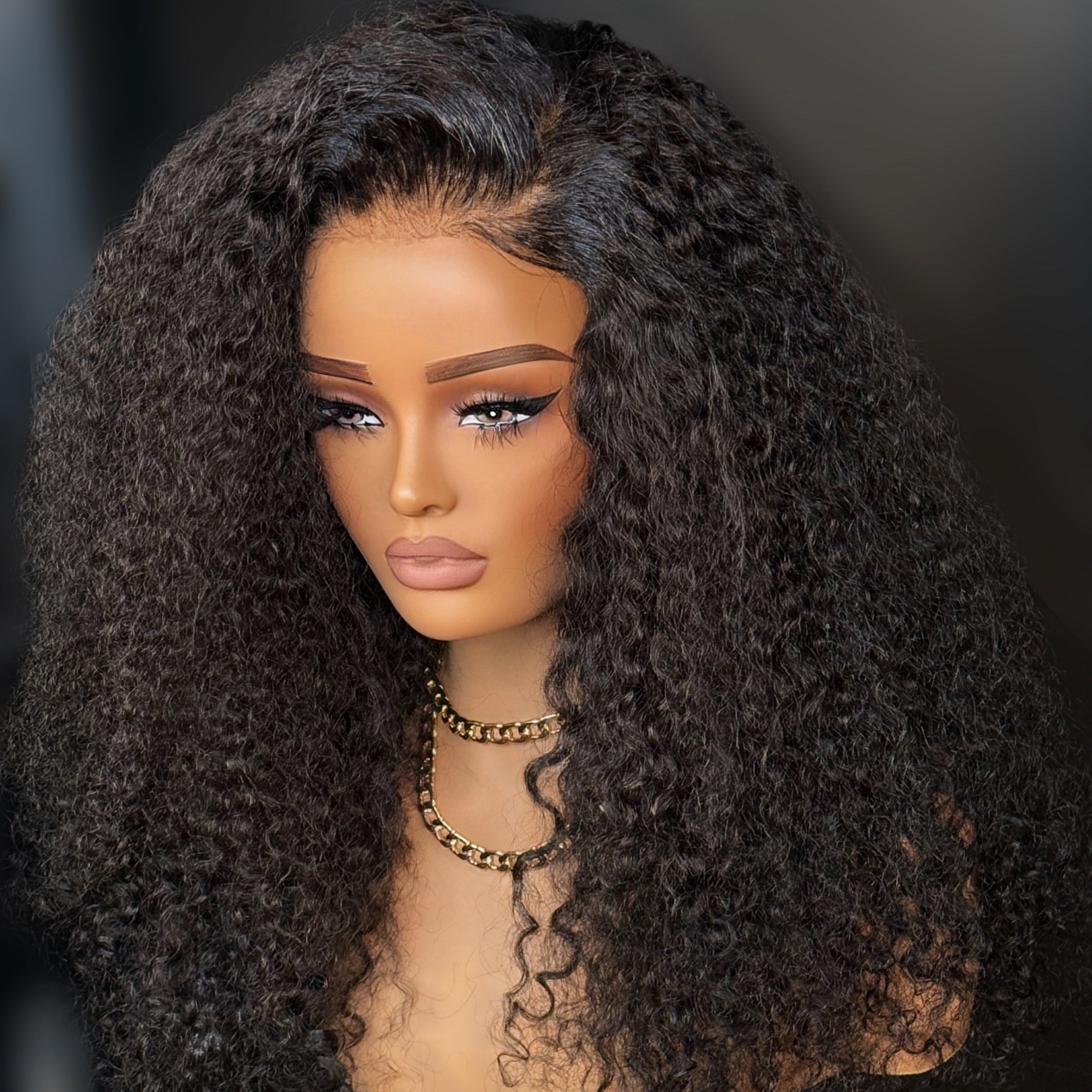 Mannequin head with a long, curly black wig on a dark background